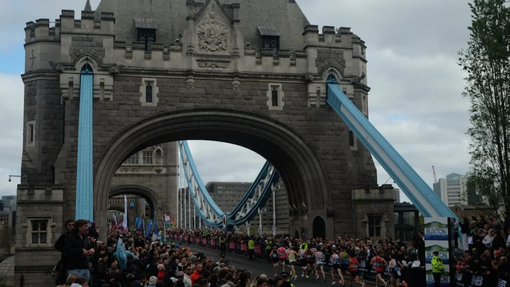 A large crowd of runners crossing the iconic Tower Bridge during a marathon event in London.