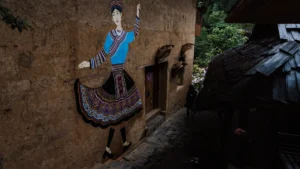 A mural of a traditional folk dancer on a building wall, representing the cultural celebration of the upcoming folk festival.