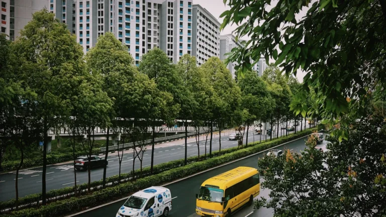 A yellow bus and a white van with blue patterns driving on a modern road.