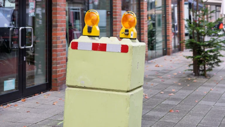Construction barriers and amber warning lights positioned on a sidewalk for upcoming roadworks in Bexley.