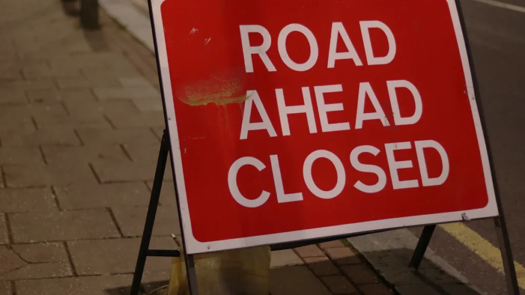 Red and white road ahead closed sign on a London city street.