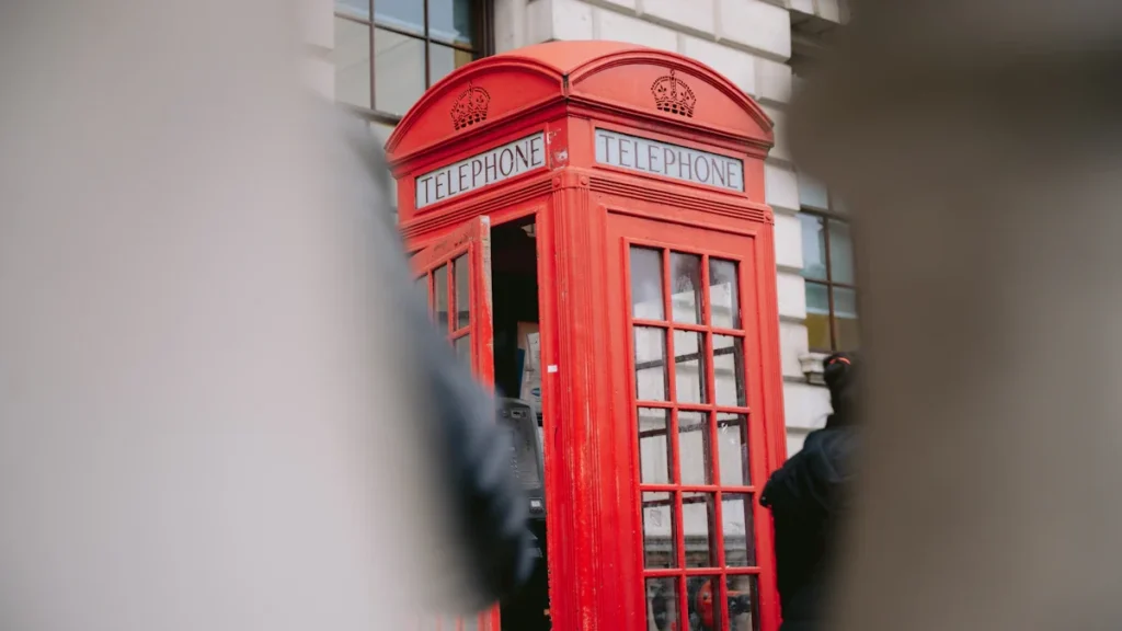 Classic red British telephone box situated on a London city street.