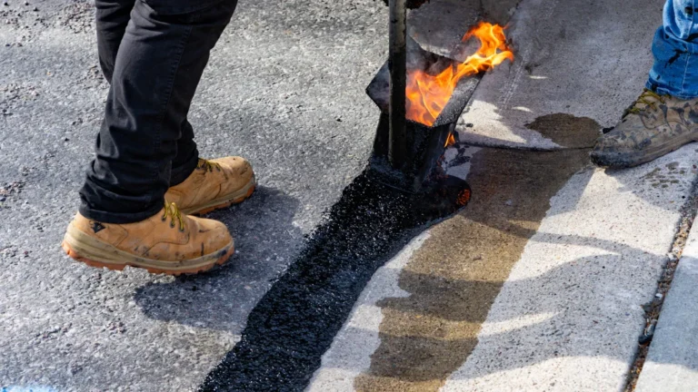 A close-up of fresh, hot asphalt being applied to a road surface during repair works.