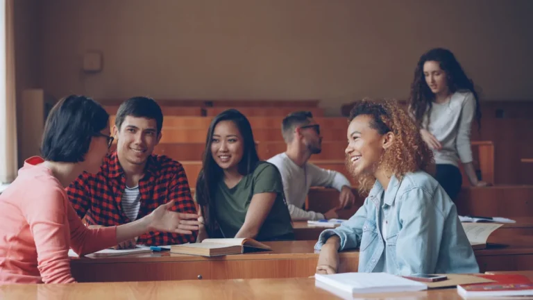 A group of young adults engaged in a friendly discussion within a tiered seating auditorium.