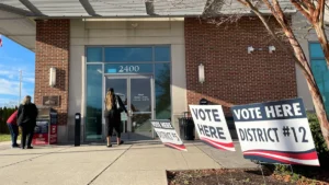 The entrance to a town hall with 'Vote Here' signs for an election.