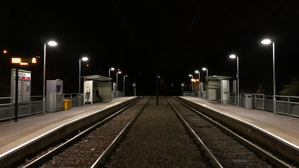 A symmetrical view of the tram tracks at Coombe Lane station in Croydon at night.