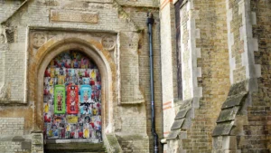 A historic stone building in Croydon with a colorful mural on the door featuring iconic red telephone boxes.