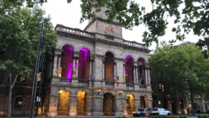 The exterior of Croydon Town Hall illuminated with purple lights in its arches.