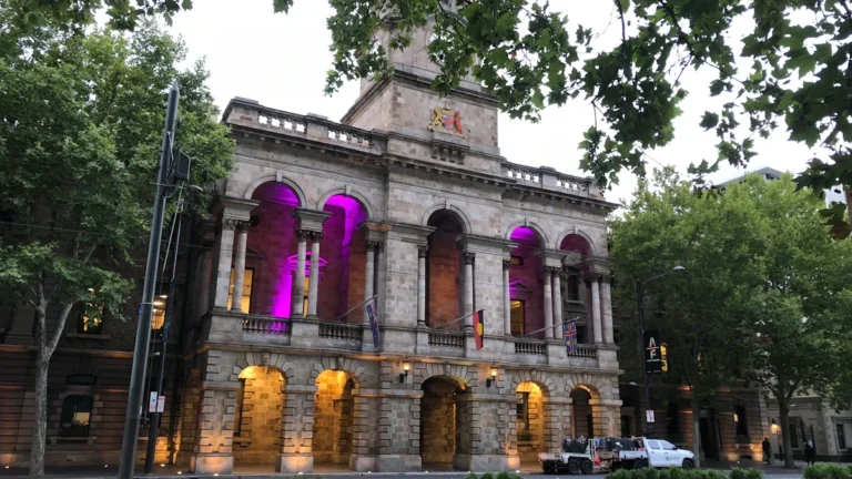 The exterior of Croydon Town Hall illuminated with purple lights in its arches.