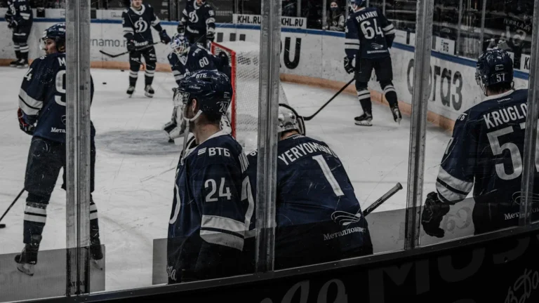 Professional ice hockey players in blue uniforms during a warm-up session on the ice rink.