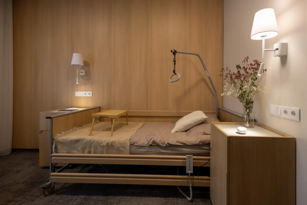 Adjustable wooden nursing bed in a cozy room with wood paneling and warm wall lighting.
