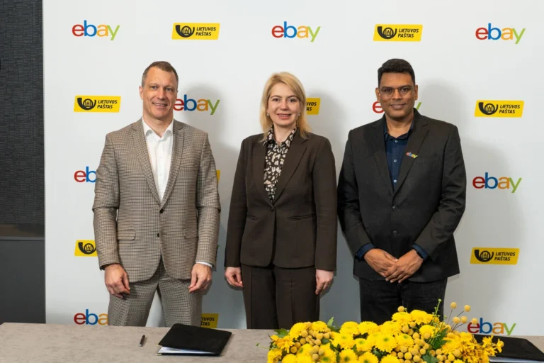Three professionals pose before a backdrop featuring repeated eBay and Lietuvos Paštas company logos.