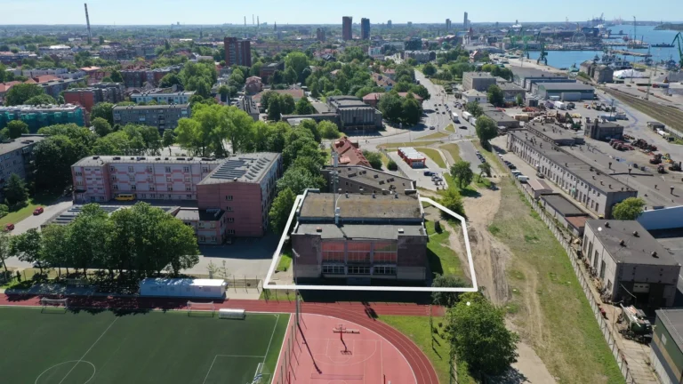 Aerial shot of an urban building highlighted by a white border near a sports field.