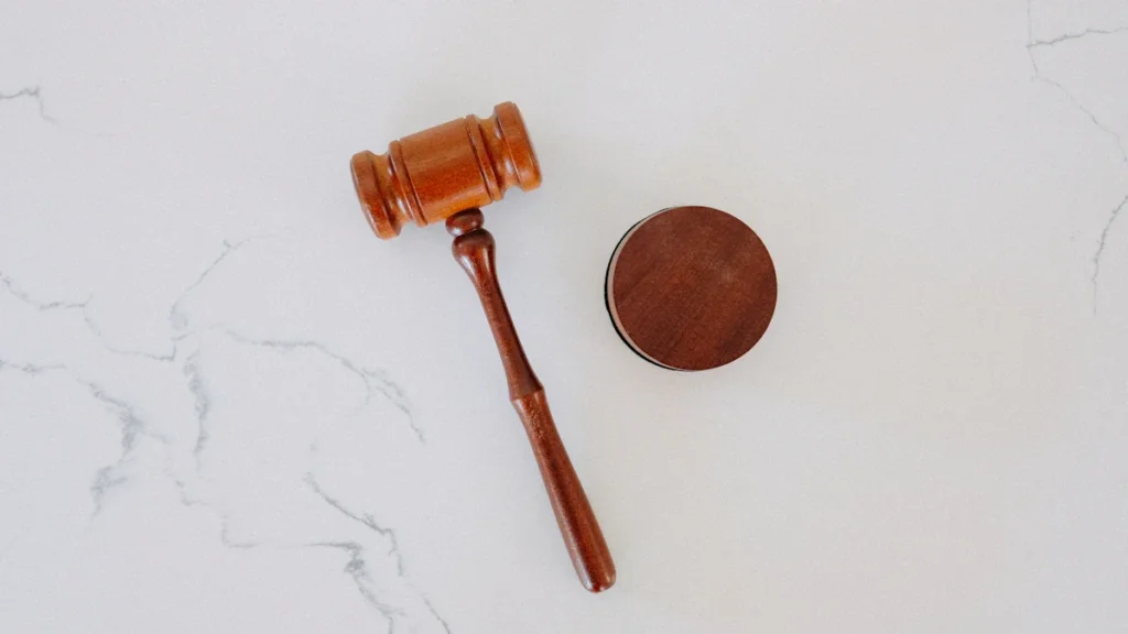 A brown wooden judge's gavel and sounding block resting on a white marble surface.
