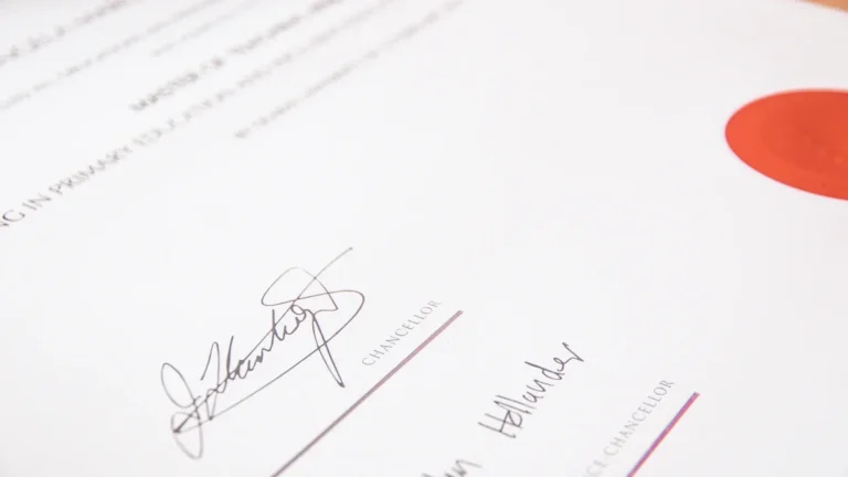 Close-up of a formal document with two handwritten signatures and a prominent red seal.