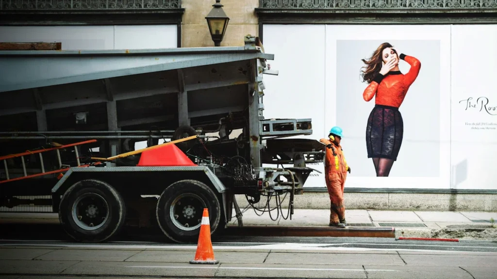 A construction worker standing next to a maintenance truck during city road repairs.