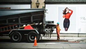 A construction worker standing next to a maintenance truck during city road repairs.