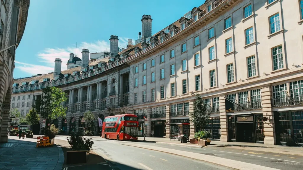 A classic red London bus on an empty street in the early morning.