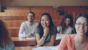 A diverse group of students smiling and engaged in a classroom setting, reflecting a positive educational atmosphere.