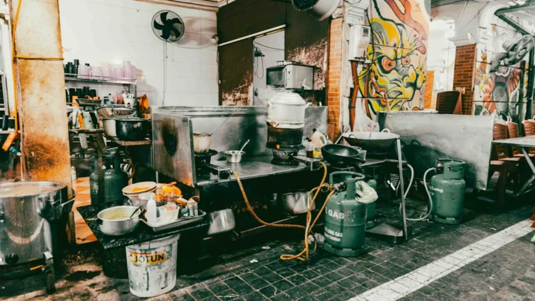 A cluttered and dirty commercial kitchen area with grime on the floor and messy surfaces.