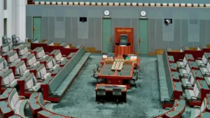 An empty legislative council chamber with green seating and desks, representing the seat of local government leadership.