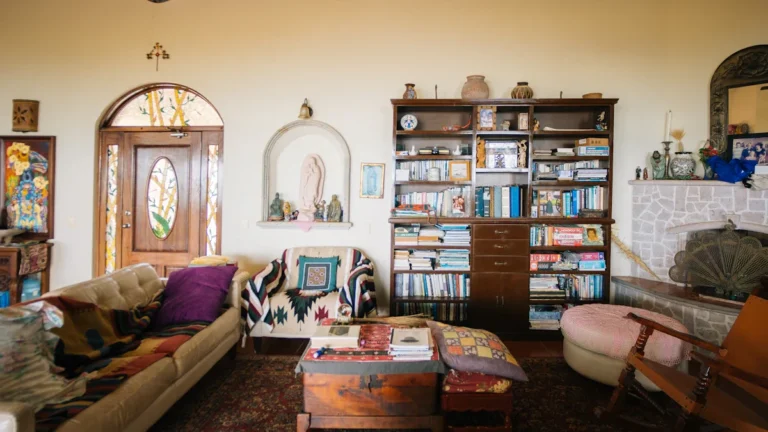 A living room densely filled with books, blankets, and various household objects, illustrating a space with significant clutter.