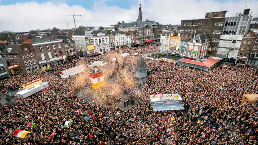Vast crowd of festival-goers gathered in a historic European city square with surrounding traditional buildings.