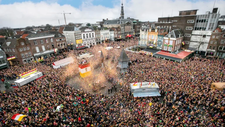 Vast crowd of festival-goers gathered in a historic European city square with surrounding traditional buildings.