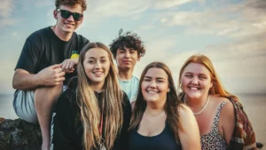 A group of smiling teenagers and young adults outdoors, representing the demographic for the Kaunas summer youth job program.