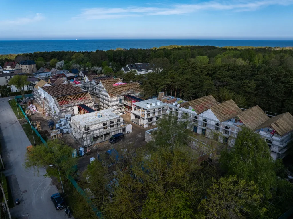 Aerial view of multi-story apartment buildings under construction near a forest and the blue ocean.