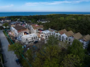Aerial view of multi-story apartment buildings under construction near a forest and the blue ocean.