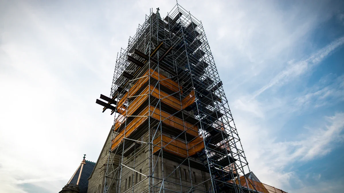 A tall church tower encased in metal scaffolding against a bright, cloudy sky, signifying restoration progress.