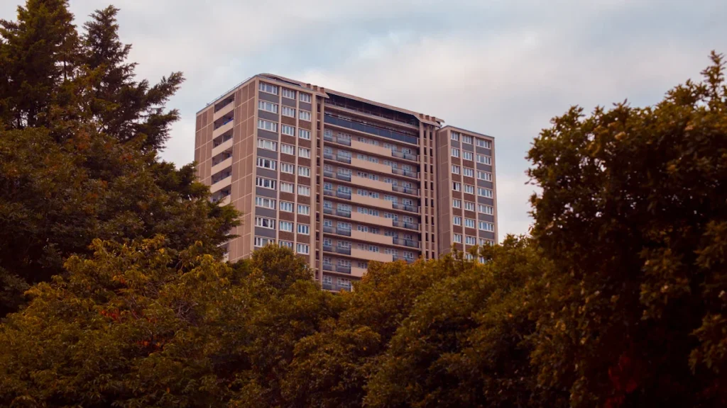 A high-rise apartment building behind a canopy of trees, representing local housing in Ealing.