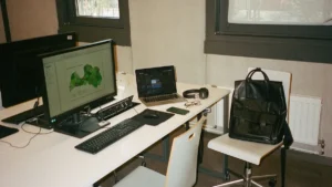 A modern workspace in Riga featuring a computer monitor displaying a green map of Latvia.