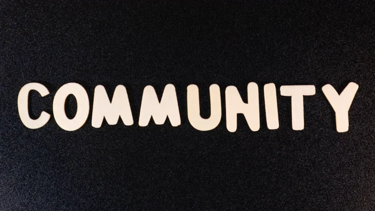 White block letters spelling the word COMMUNITY centered on a dark, textured black background.