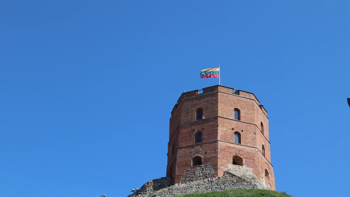 The historic red brick Gediminas Tower in Vilnius with the Lithuanian flag flying against a blue sky.