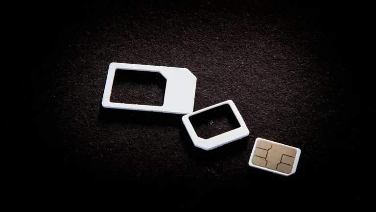 A close-up of a mobile SIM card and its various adapter frames on a dark, textured background.