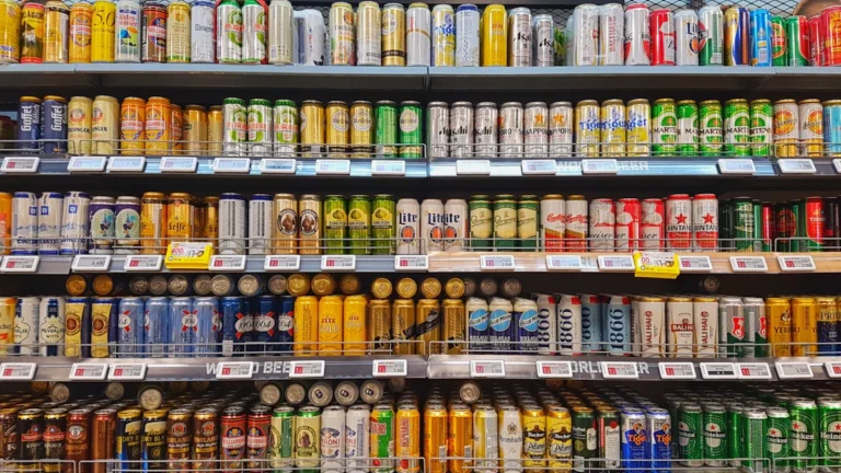 Rows of various colorful beer cans neatly organized on shelves in a retail store.