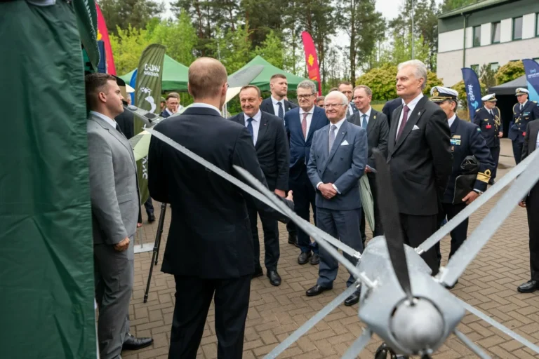 King Carl XVI Gustaf and President Gitanas Nausėda observe a military drone during an outdoor presentation.