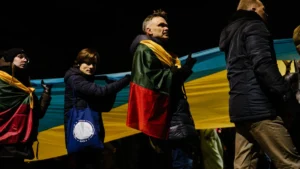 People in Lithuania carrying a large Ukrainian flag at night, representing the unity between both nations.