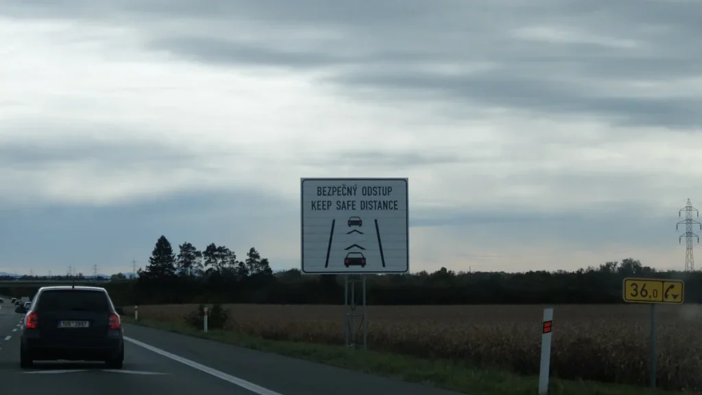 A highway road sign in English and Czech reminding drivers to keep a safe distance.