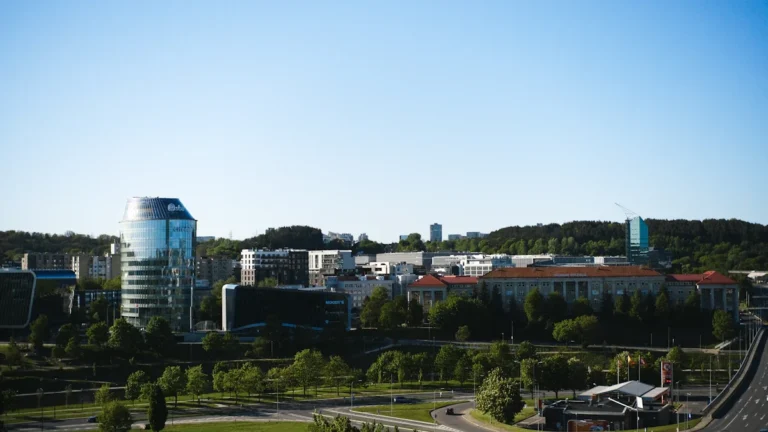 A panoramic view of the modern Vilnius skyline in Lithuania, featuring contemporary glass buildings and lush green spaces.