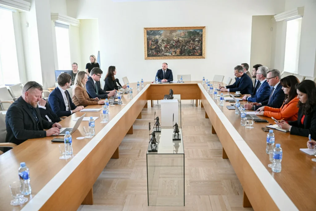 Professionals seated at a U-shaped wooden table during a formal meeting in a brightly lit room.