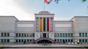A stately stone building in Lithuania with the national yellow, green, and red colors displayed on the facade.