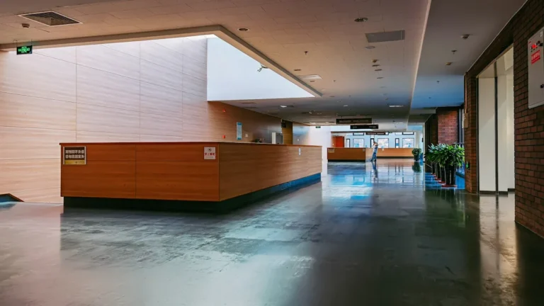 A modern, minimalist wooden reception desk in a brightly lit medical clinic or public facility.