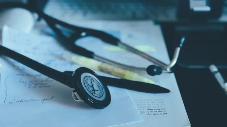 A medical stethoscope resting on top of a stack of documents and a book.