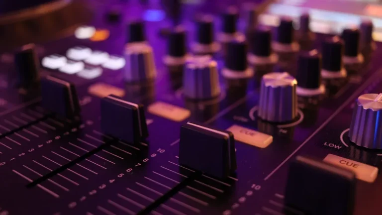 A professional sound mixing console with illuminated buttons and faders in a recording studio.