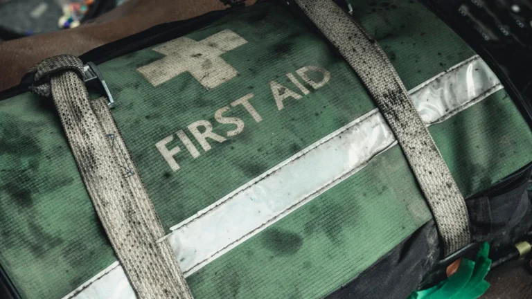 A worn green first aid bag featuring a white cross and the words FIRST AID.