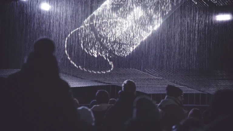 A person silhouetted against a large, glowing digital light projection on a stage in Vilnius, Lithuania.
