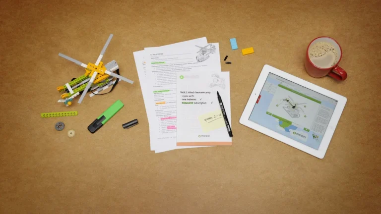 A top-down view of a teacher's desk featuring lesson plans, a tablet, and a coffee mug.